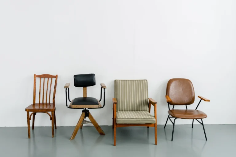 Four vintage chairs in different styles arranged against a white wall